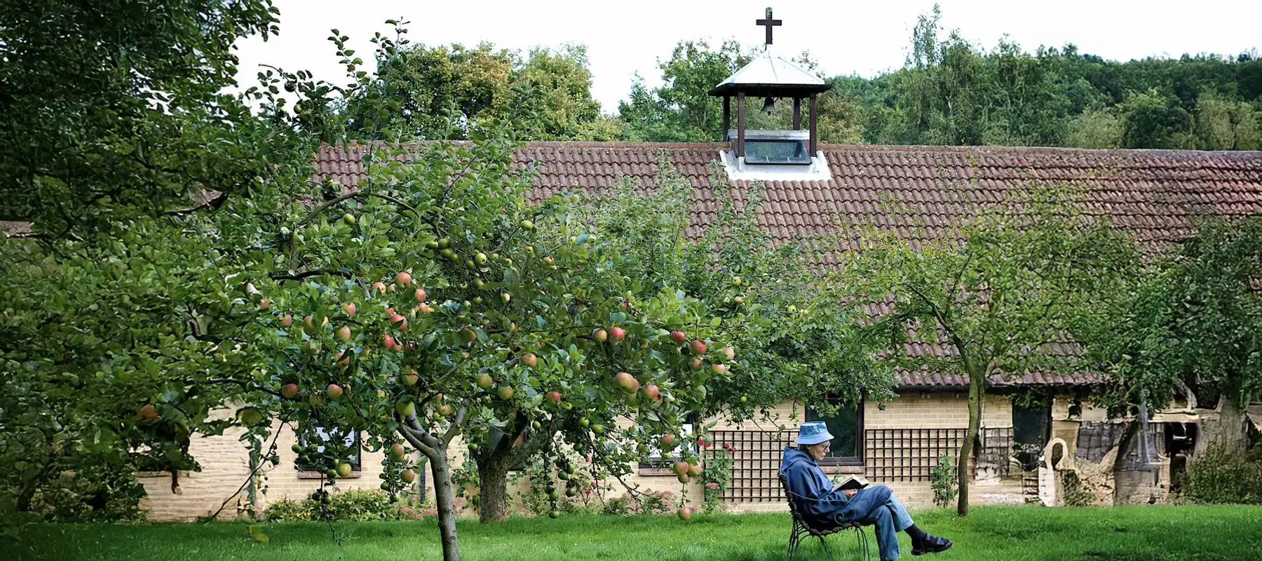 Man reading a bible in the orchard of Crawley Down Monastery